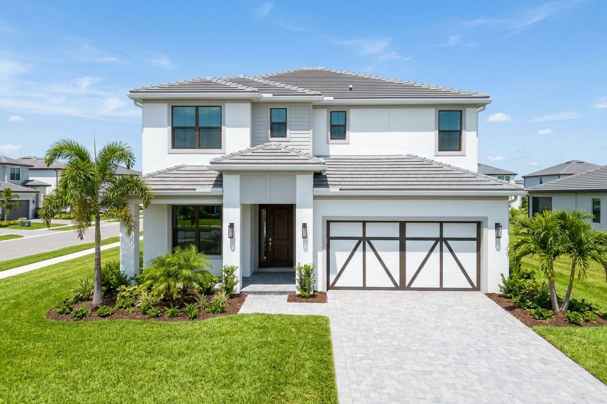 A brand-new two-story white Florida home with a two-car garage, paver driveway and young palm trees in a new neighborhood